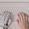 picture of a computer keyboard with a robotic and human hand