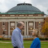 Jean and Steve Kaplan hold hands in front of Foellinger Auditorium