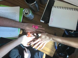 Hands of UIUC MFA poets on the workshop table